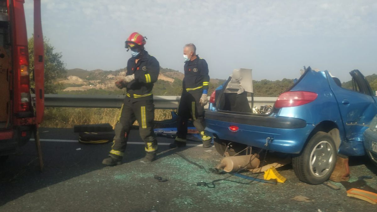 Dos bomberos junto a uno de los vehculos implicados 